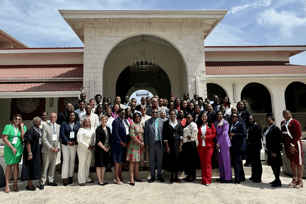 Group of professionally dressed people posing outside a stone building with arches and chandeliers in the background, sunny day.
