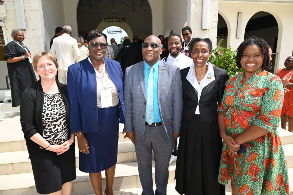 Group of six adults in formal clothing posing on steps outside a building at a social event.
